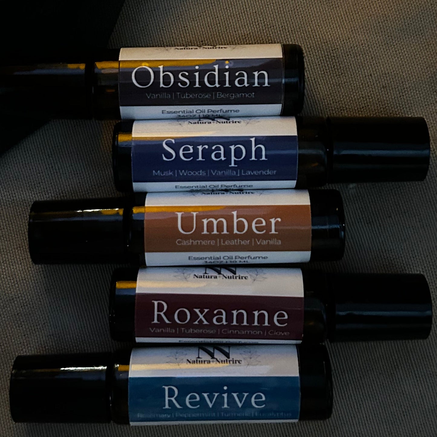 Set of black rollerball bottles with colorful labels on a dark surface