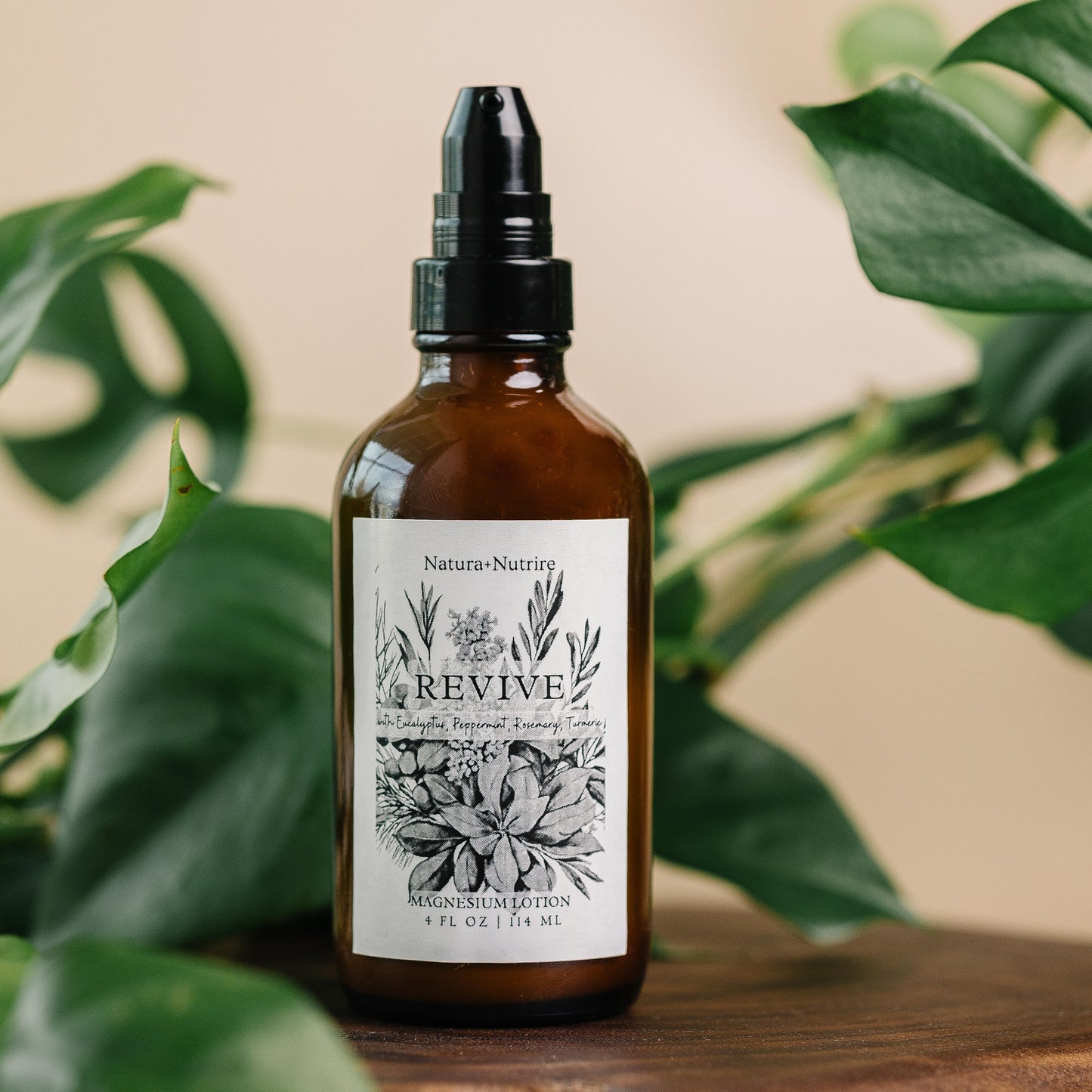 Brown glass bottle with a label on a wooden surface with green leaves in the background