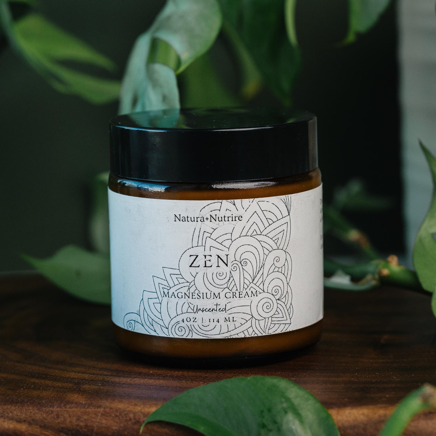 Jar of Nature's Nature Zen Magnesium Cream on a wooden surface with green leaves in the background
