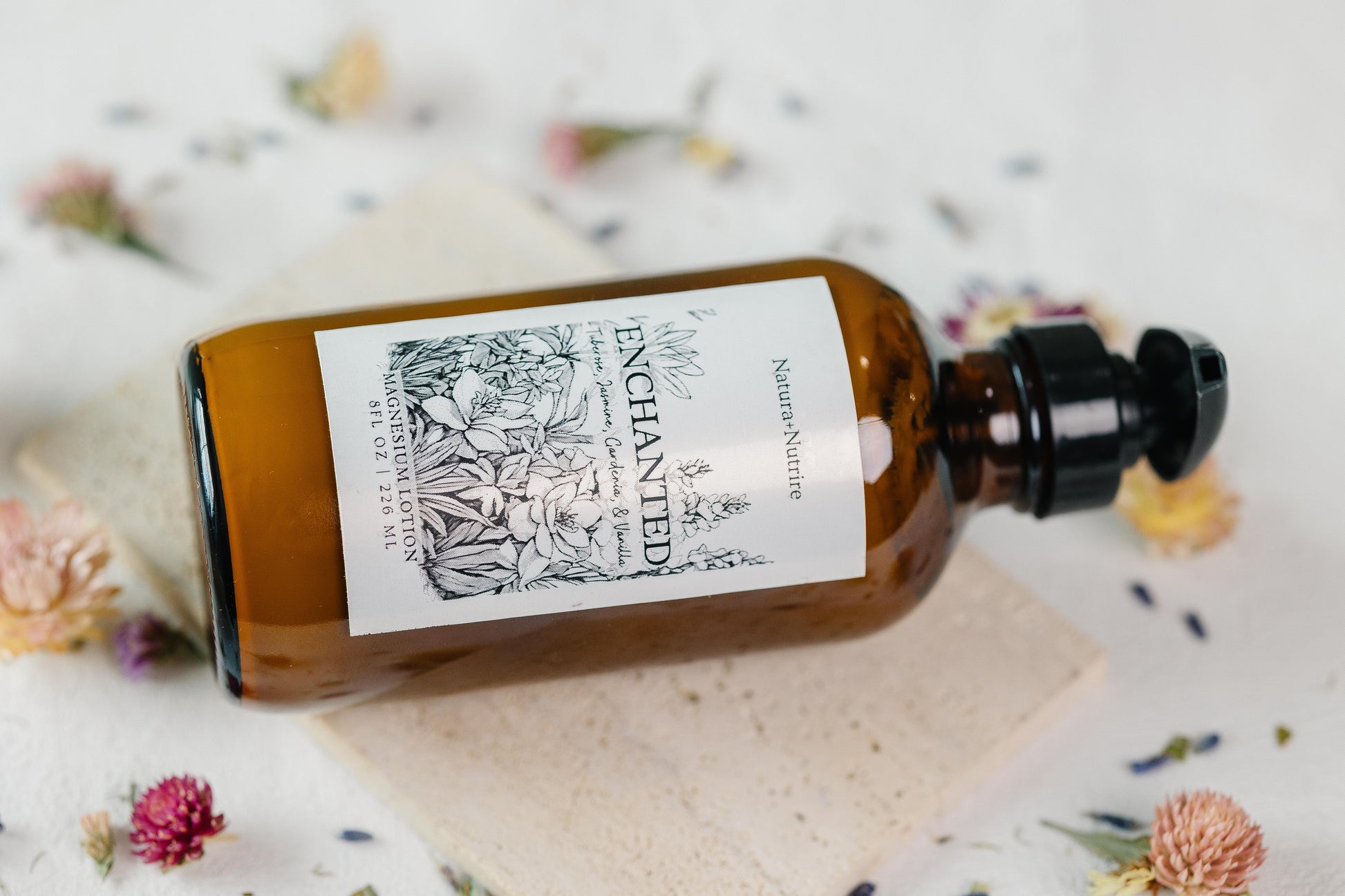 Brown glass bottle with a label on a white surface with flowers