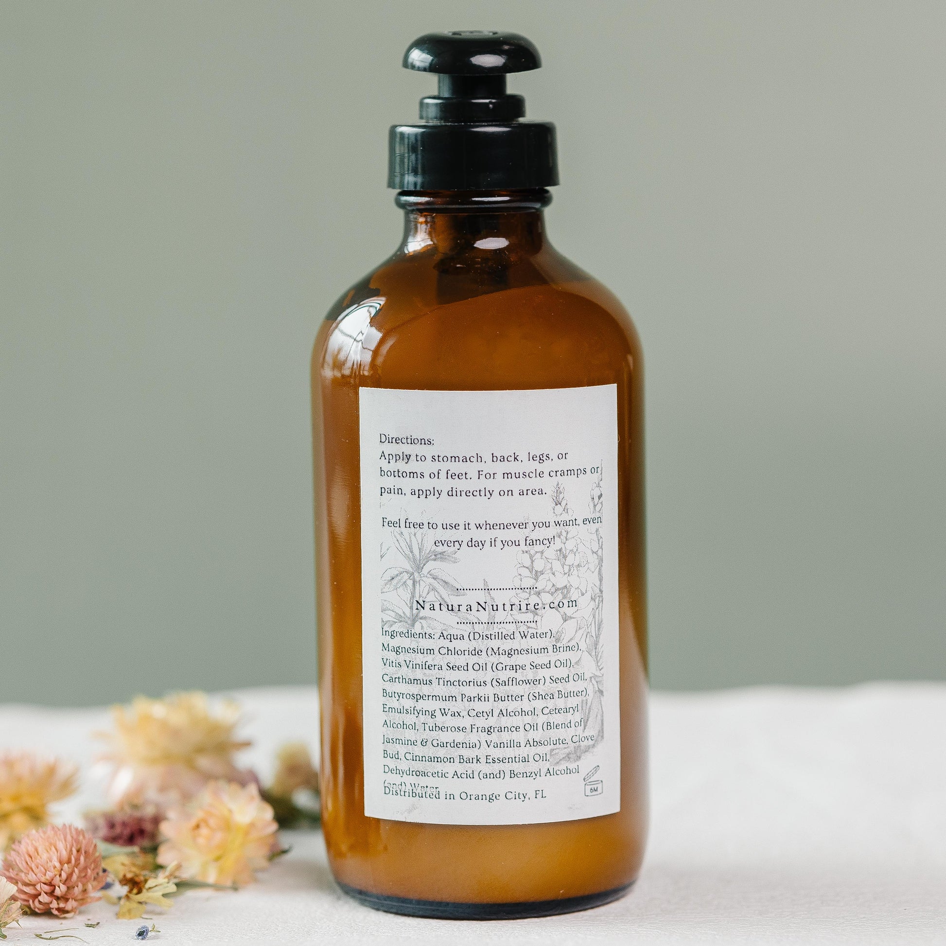 Brown bottle with a label on a white surface with flowers