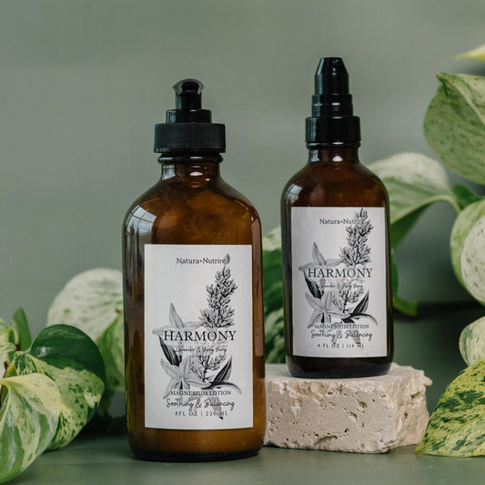 Two brown bottles labeled 'Harmony' with plant-themed designs on labels, surrounded by green leaves.