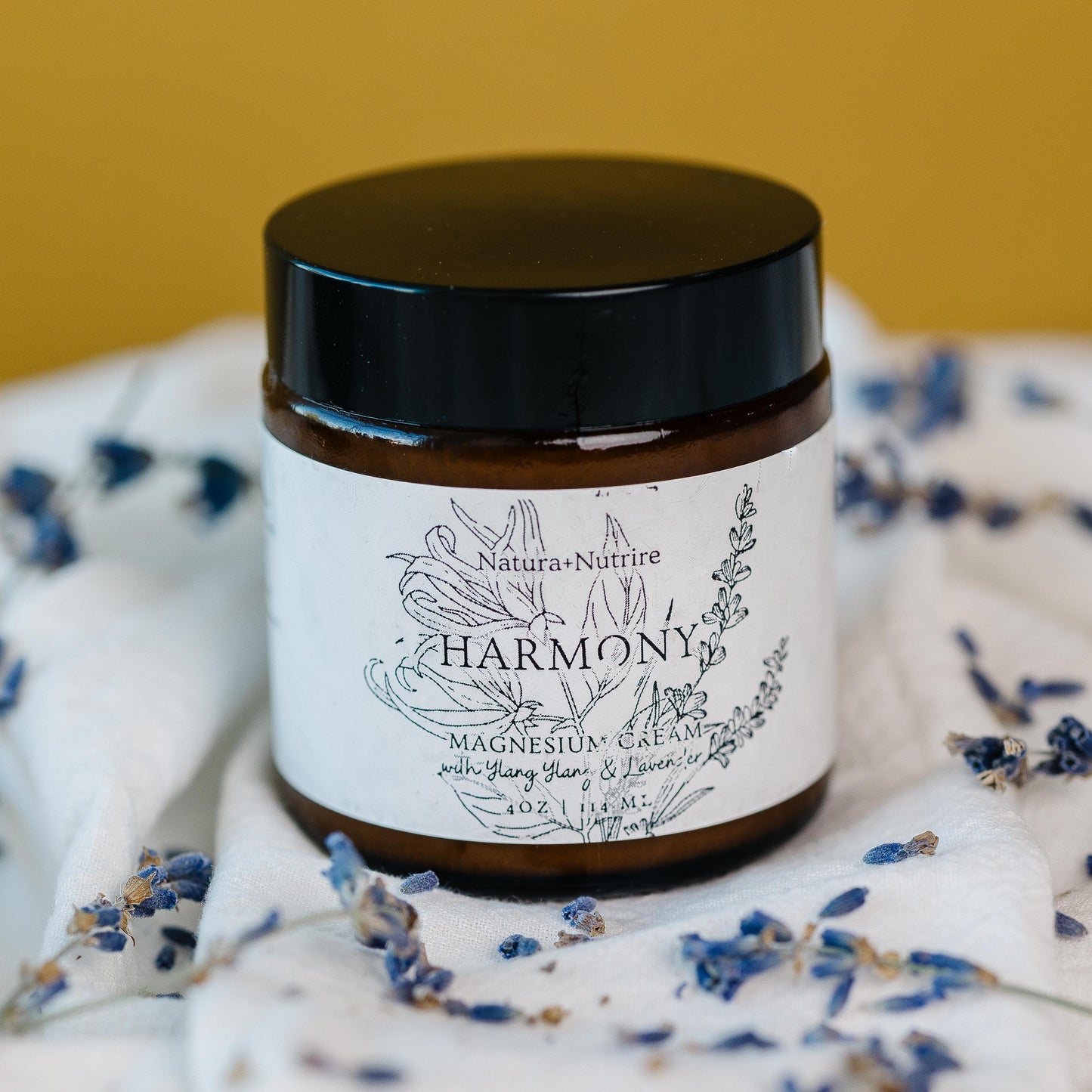 Jar labeled 'Harmony' surrounded by dried lavender on a white fabric background