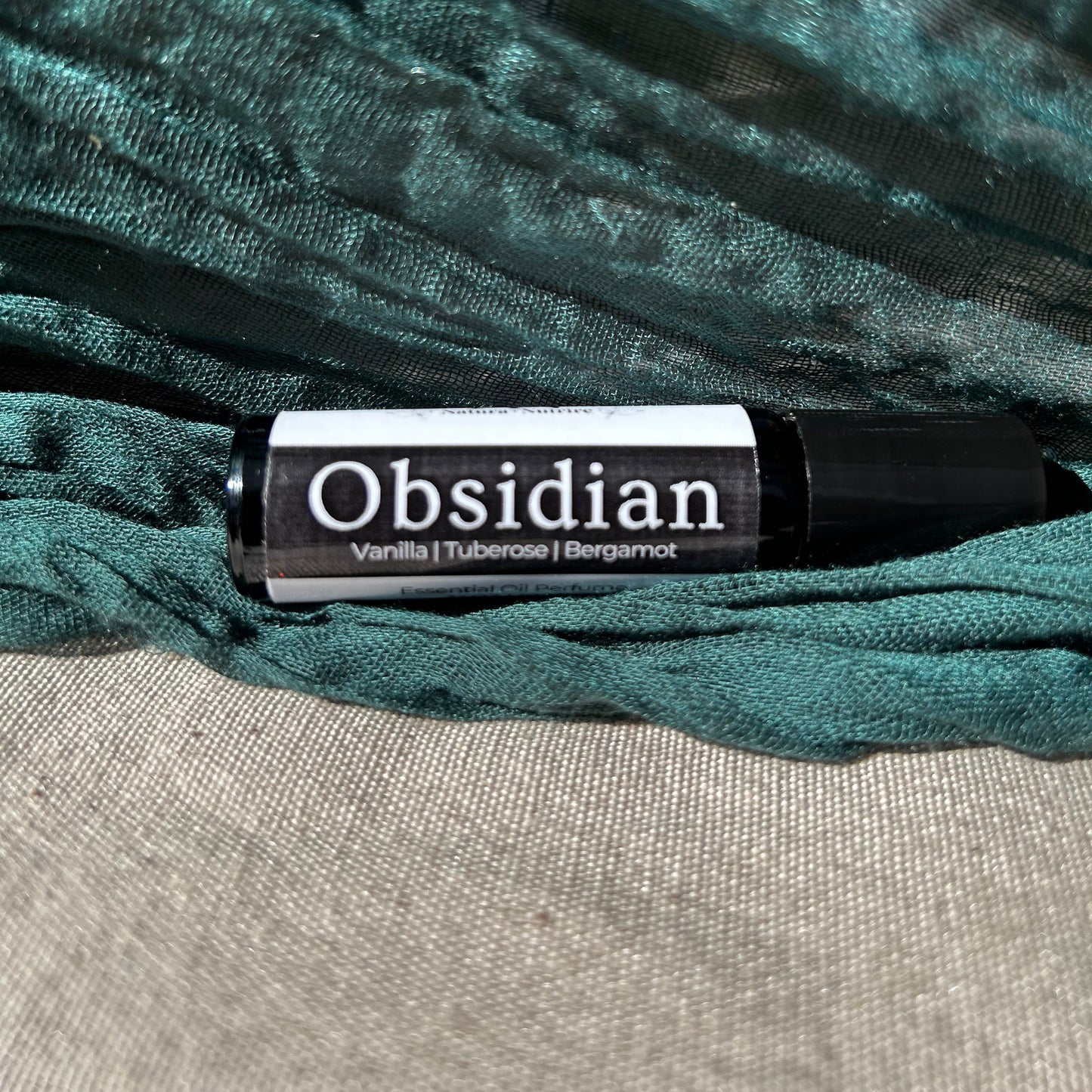 Obsidian perfume bottle on a textured green fabric background