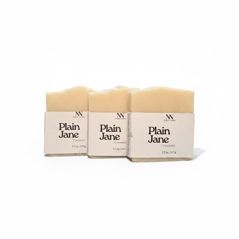 Three Plain Jane Unscented Handcrafted Soap bars wrapped in kraft paper sleeves, side by side on a white background