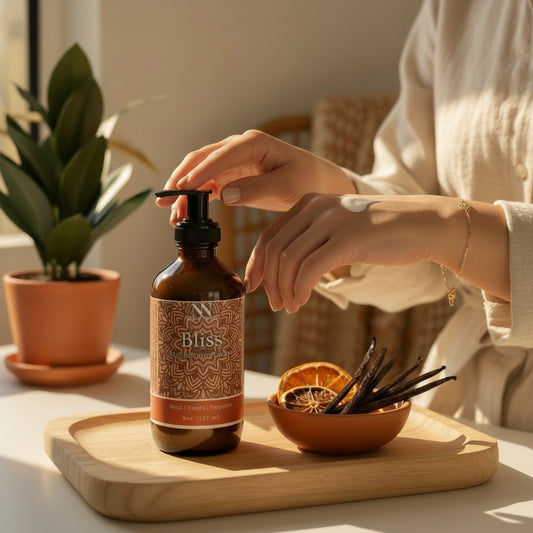 Hands applying Bliss Magnesium Lotion at a wooden table with dried orange slices, vanilla beans, and a potted plant