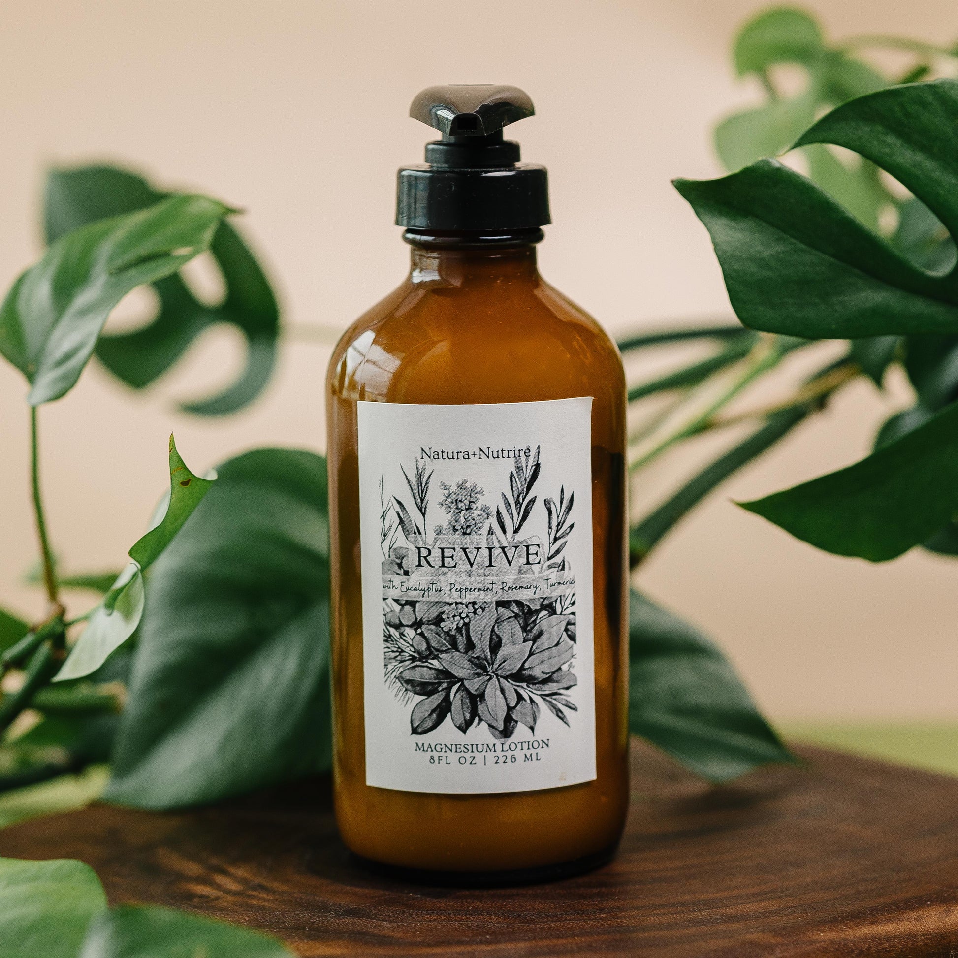 Brown bottle with black pump and botanical label on a wooden surface with green leaves in the background