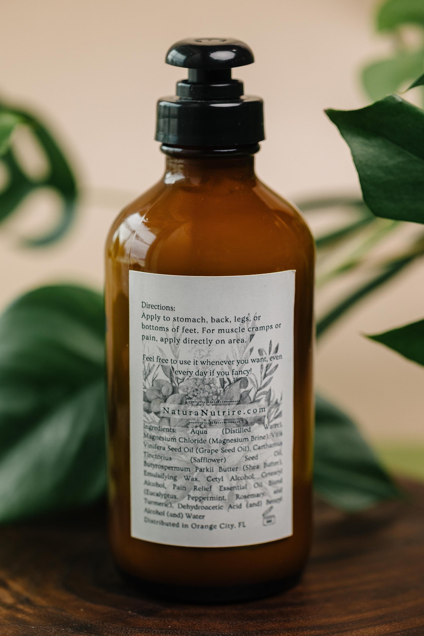 Brown bottle with a label on a wooden surface with green leaves in the background