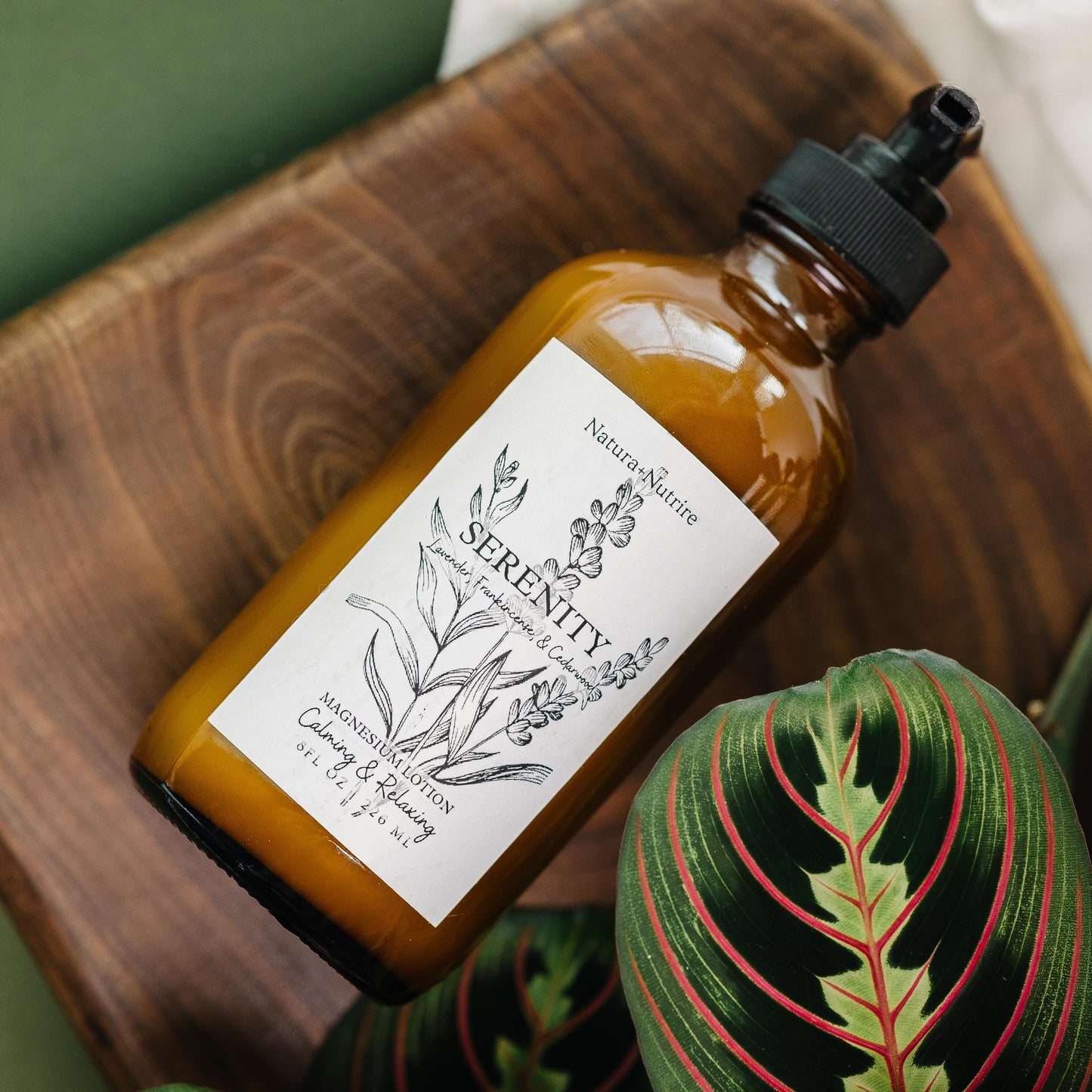 Brown bottle labeled 'Serenity' on a wooden surface with plants in the background