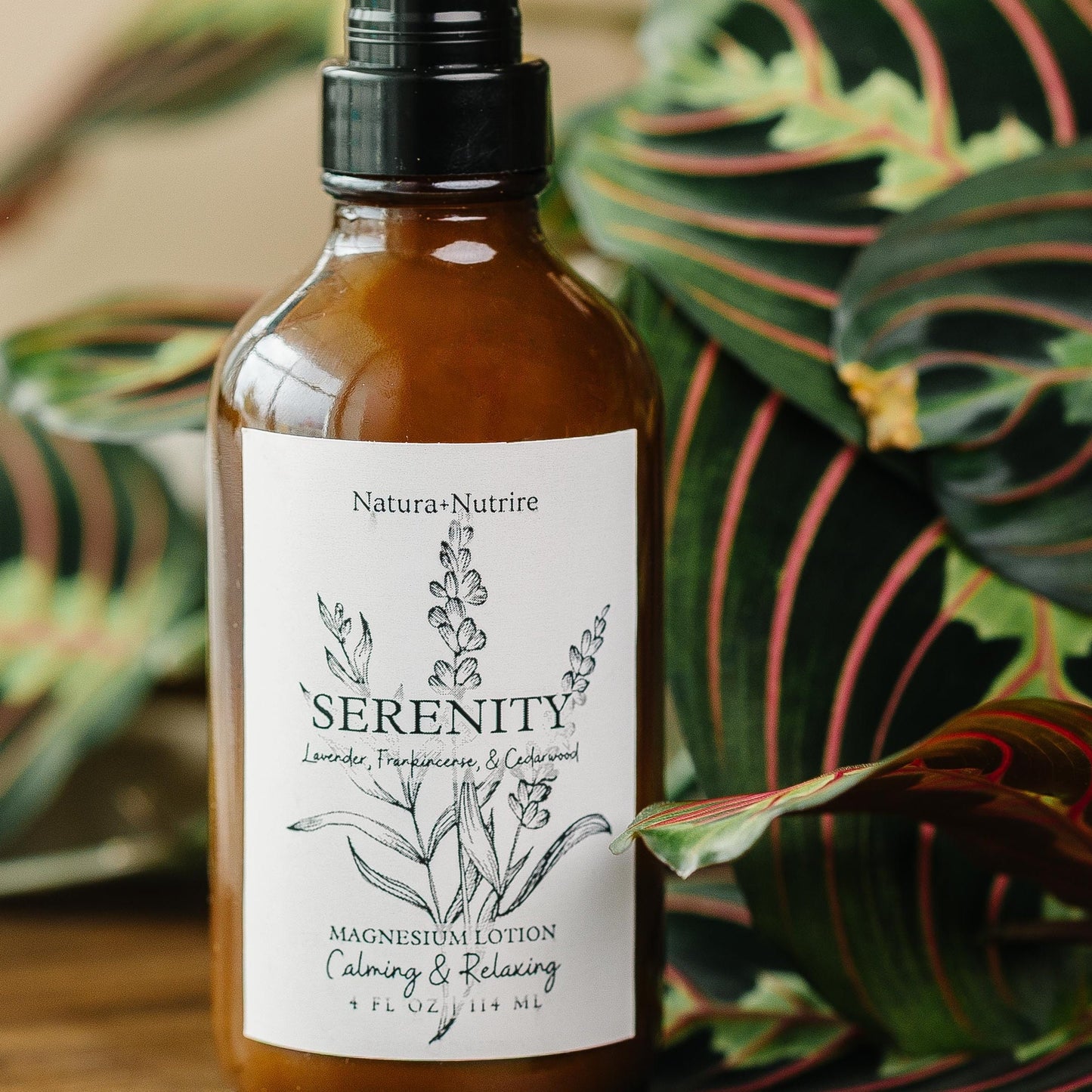 Serenity bottle on a wooden surface with green leaves in the background