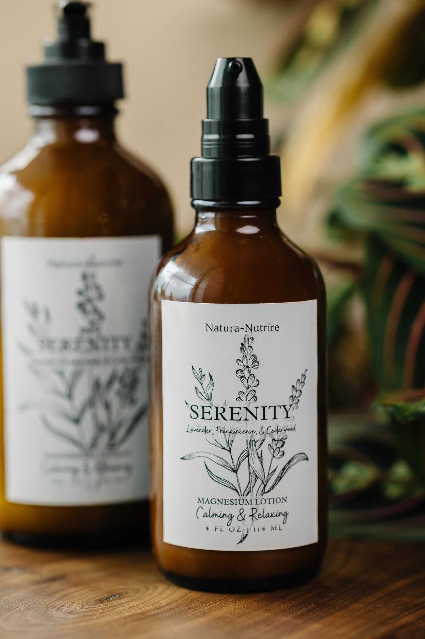 Two bottles of Natura-Nutrire Serenity magnesium lotion on a wooden surface with a blurred natural background.