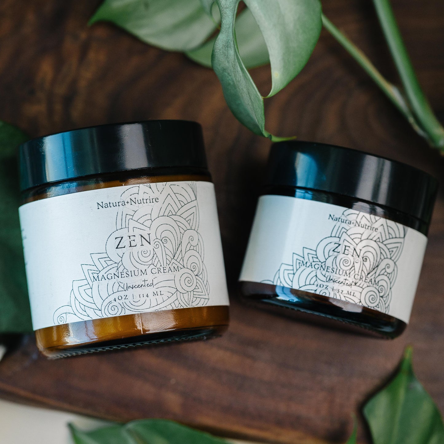 Two jars of 'Zen' cream on a wooden surface with green leaves around.