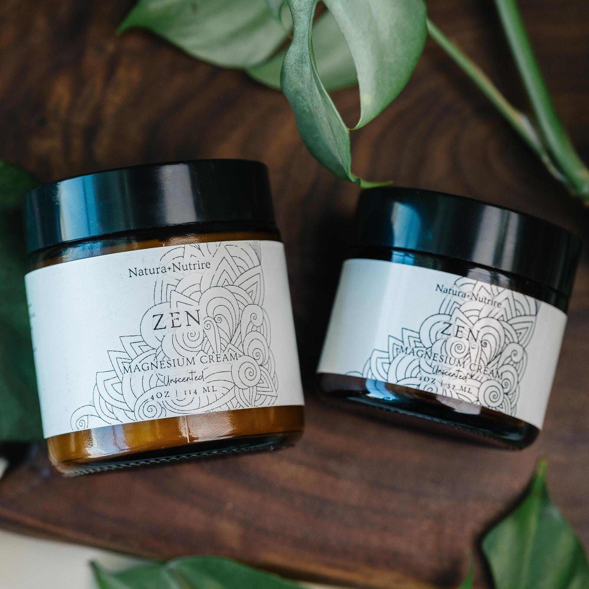 Two jars of 'Zen' cream on a wooden surface with green leaves around.