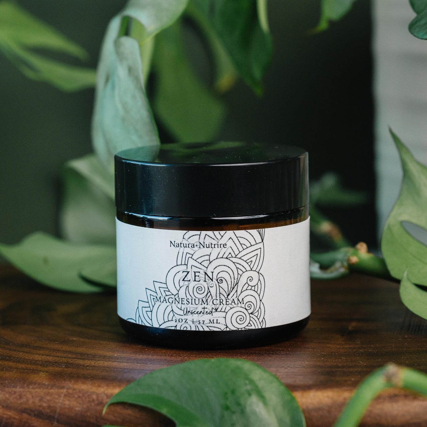 Jar of Natura Nutrire Zen Magnesium Cream on a wooden surface with green leaves in the background