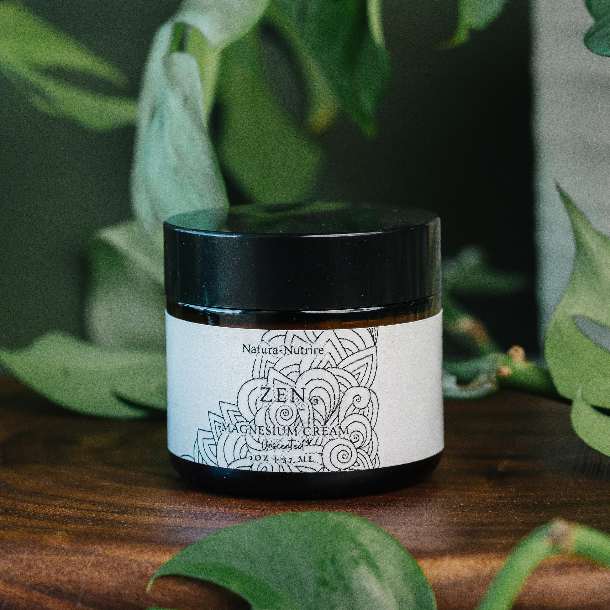 Jar of Natura Nutrire Zen Magnesium Cream on a wooden surface with green leaves in the background