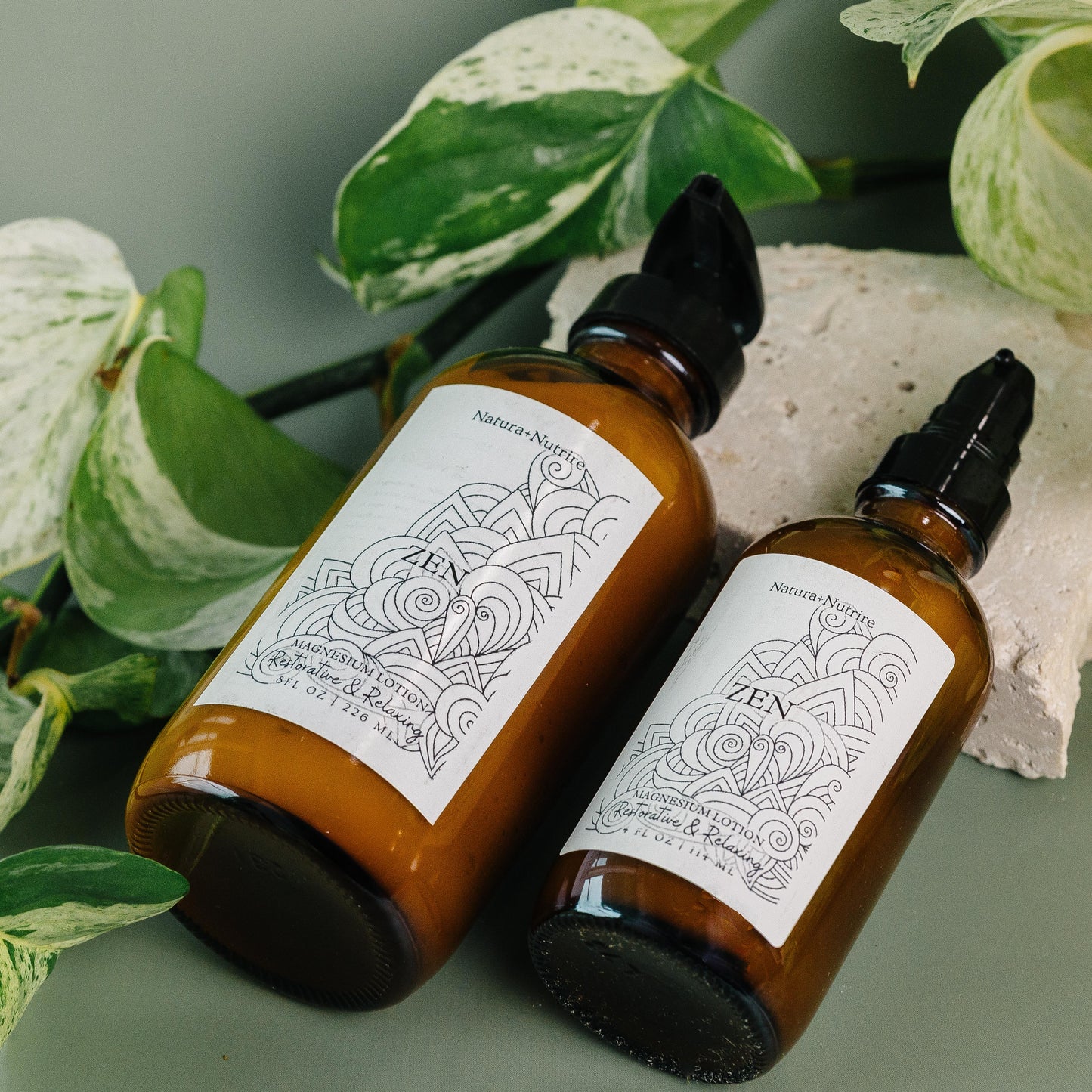 Two brown bottles with labels on a green surface with leaves