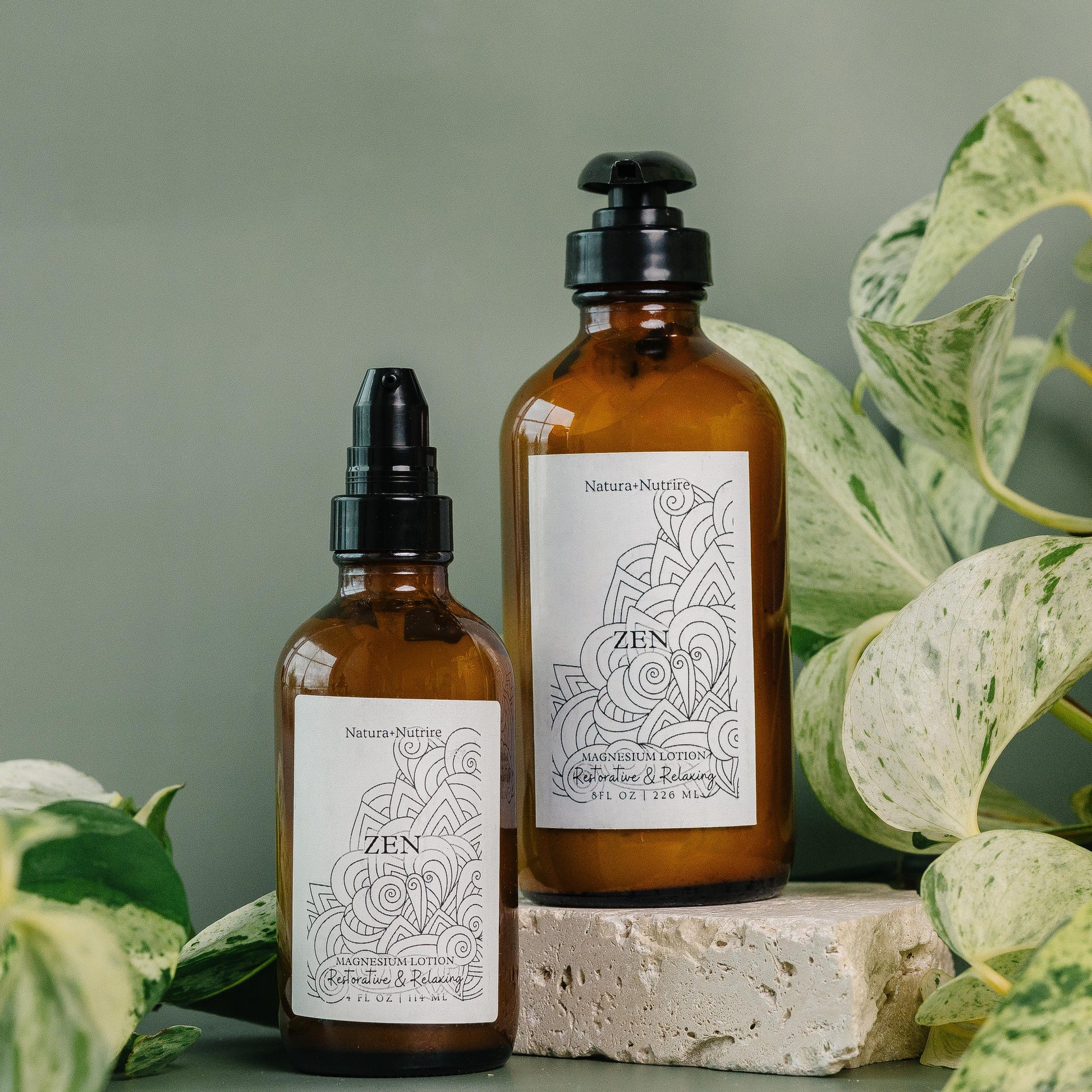 Two brown bottles with labels on a surface with green leaves in the background