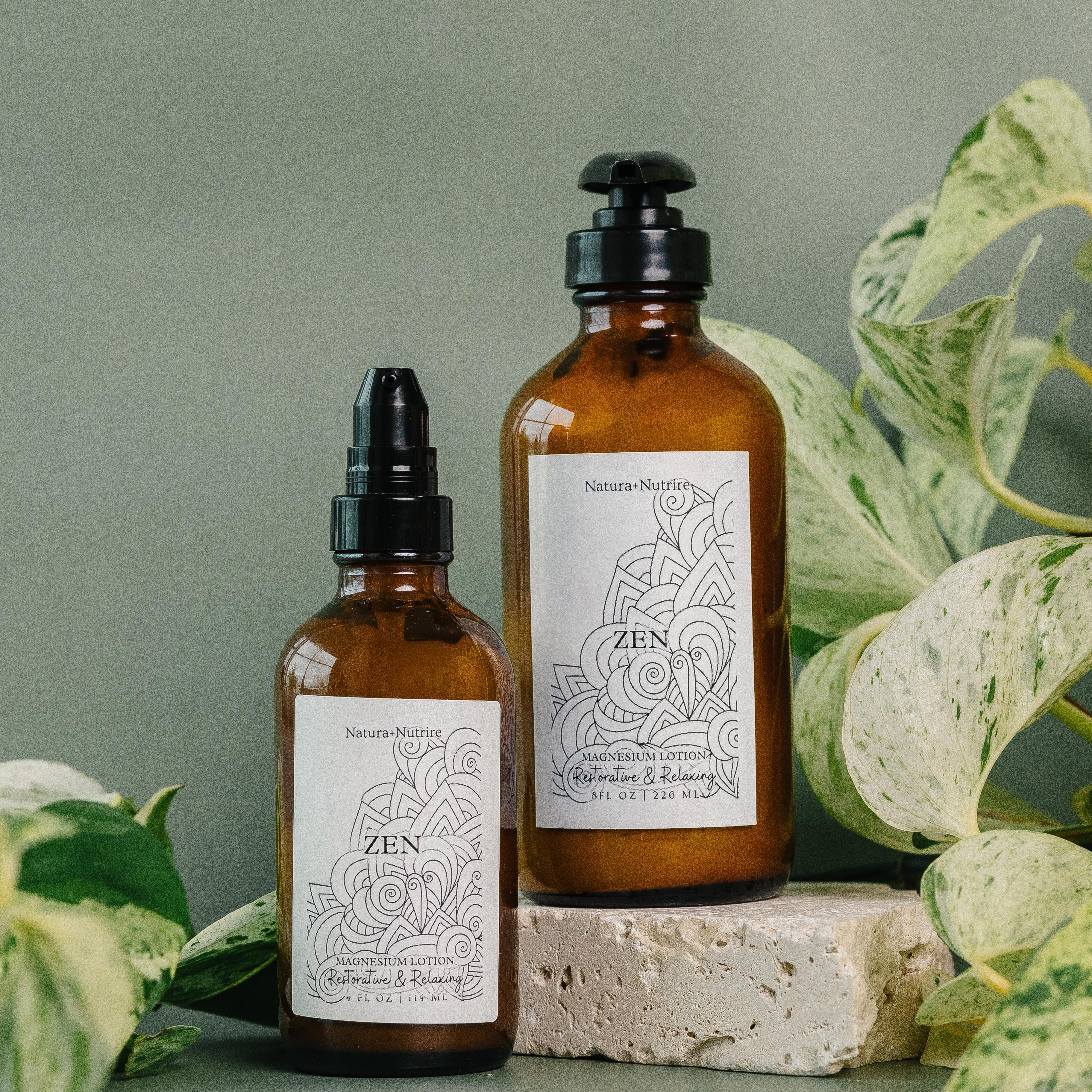 Two brown bottles with labels on a surface with green leaves in the background