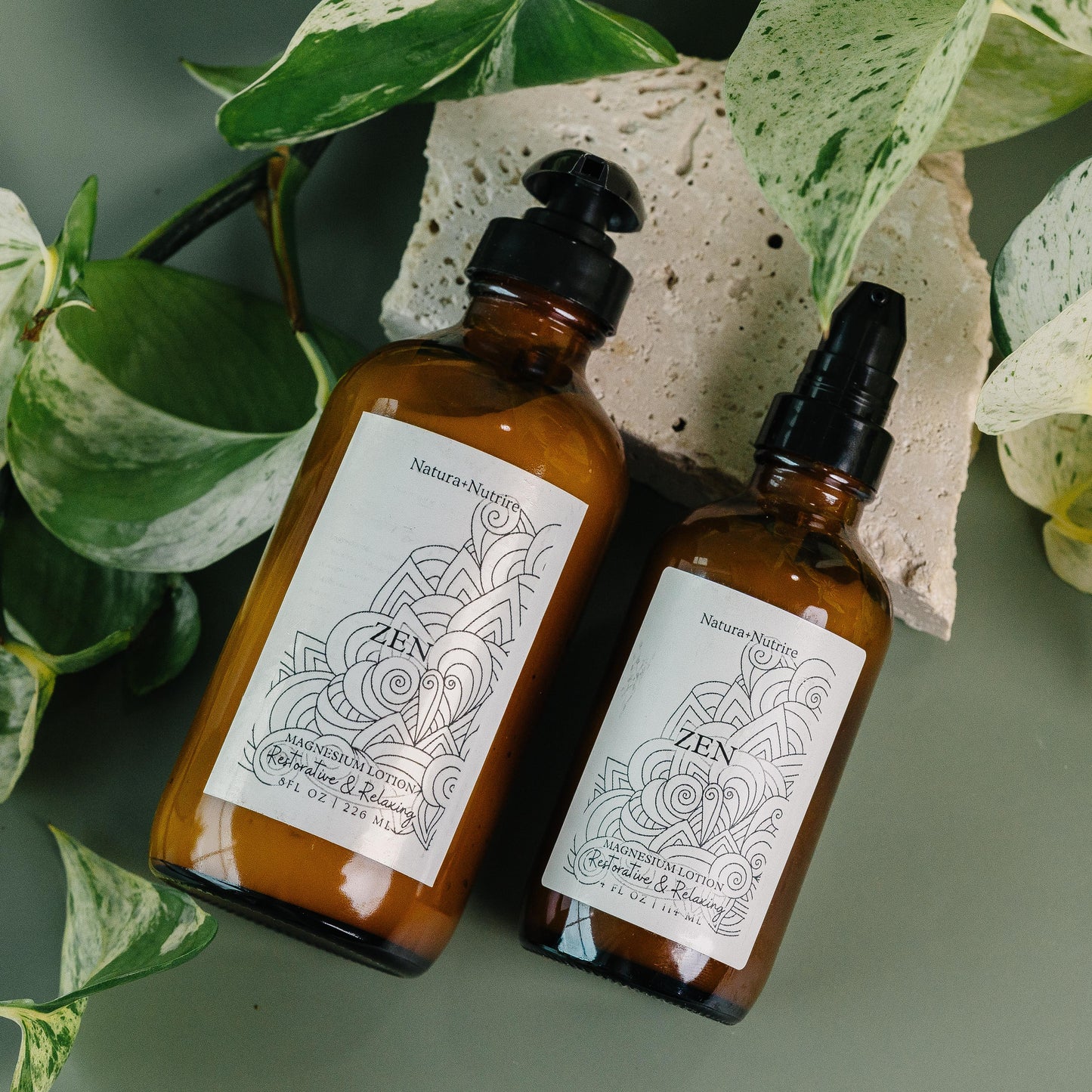 Two brown bottles with black pump and dropper heads on a green background with leaves.